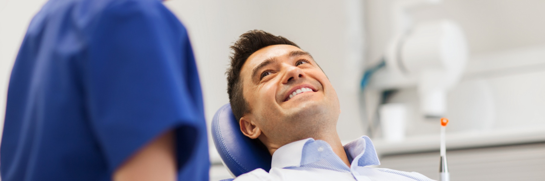 Smiling man relaxed in a dental chair looking up at his dentist during an appointment
